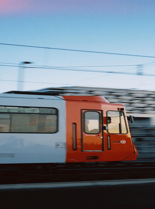 Vista laterale di un treno arancione e bianco che sfreccia con effetto di movimento.
