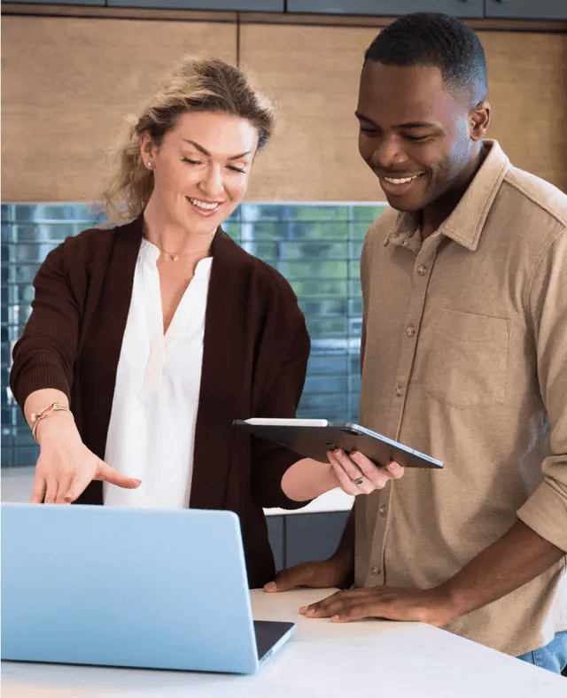 Uomo e donna sorridono mentre guardano un laptop.